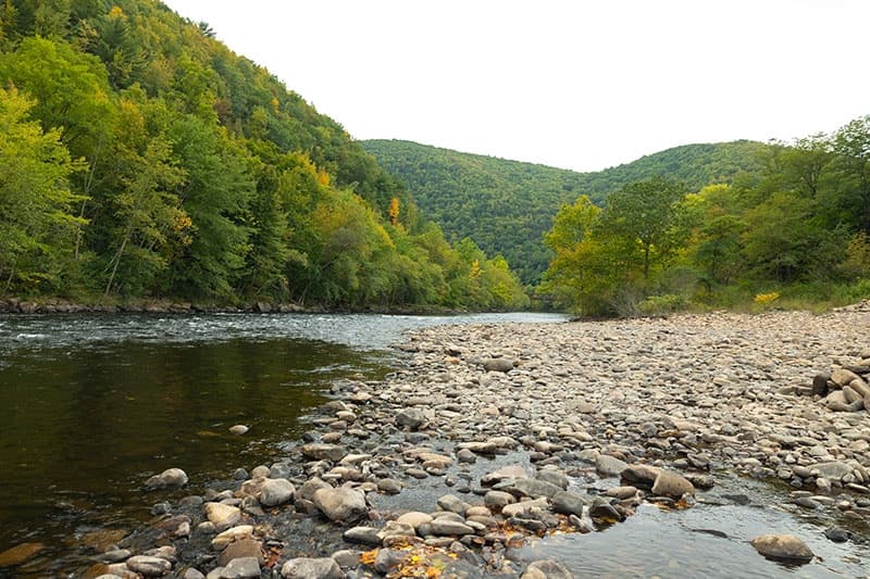 Rocky river channel with rolling forested hills and shoreline