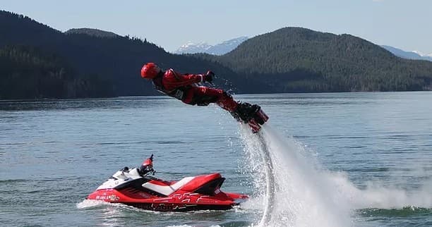 Flyboarder soaring above Montana lake with forested mountain backdrop