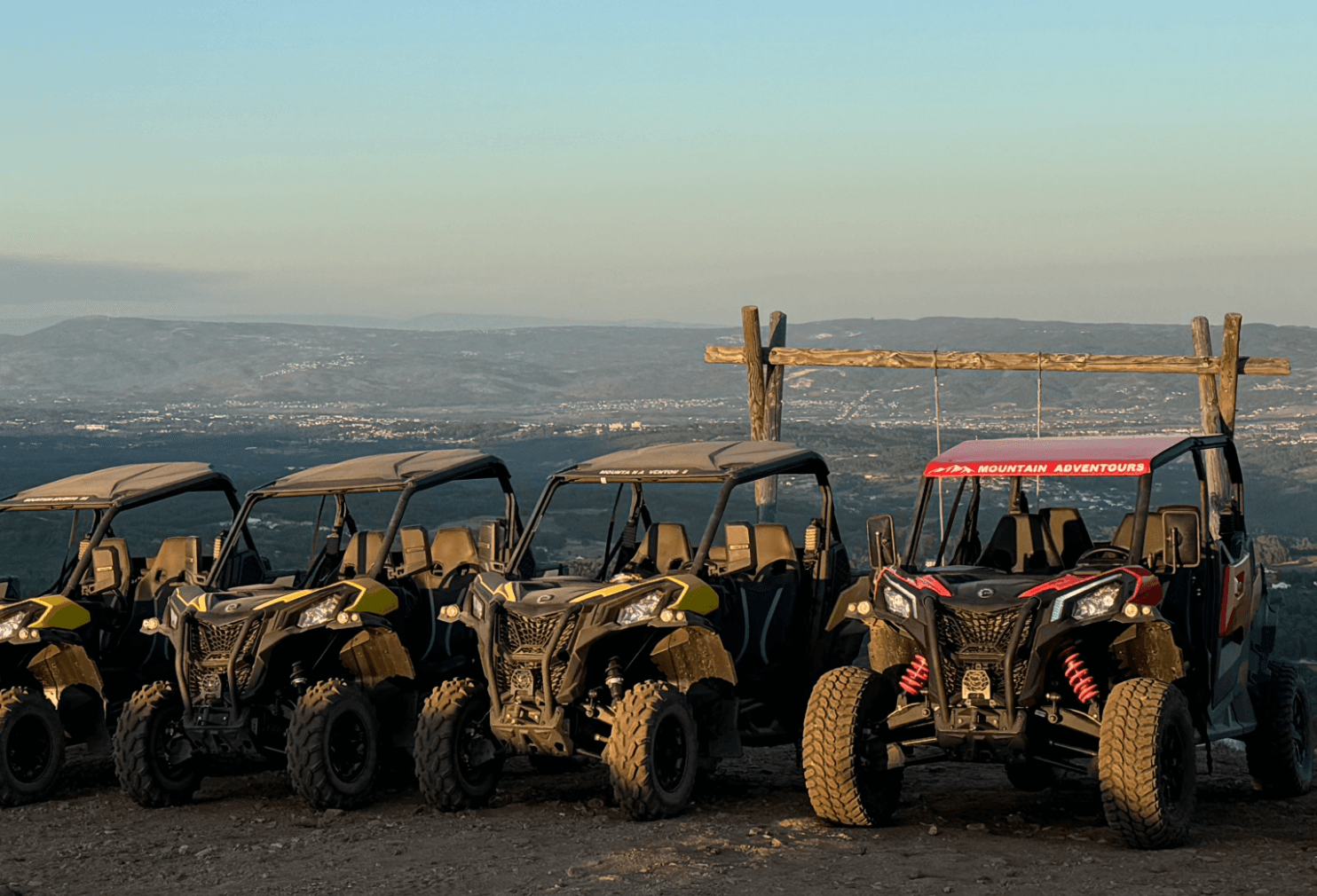 UTV lineup at sunset on mountain ridge with valley vista