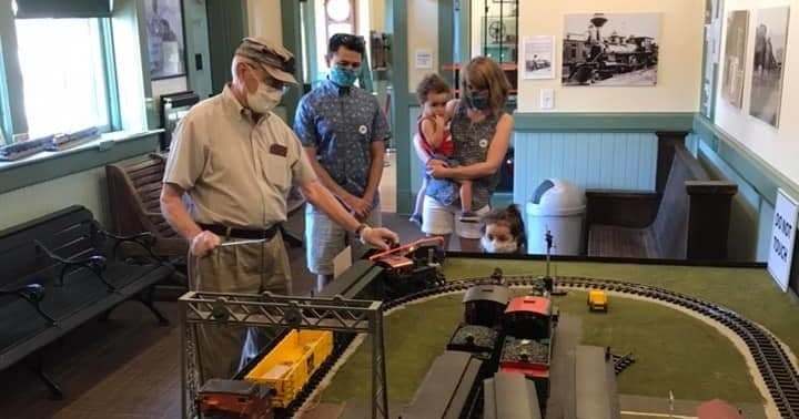 Visitors viewing model train layout inside railroad museum exhibit