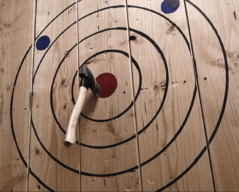 Close-up wooden target rings with axe lodged in center, indoor