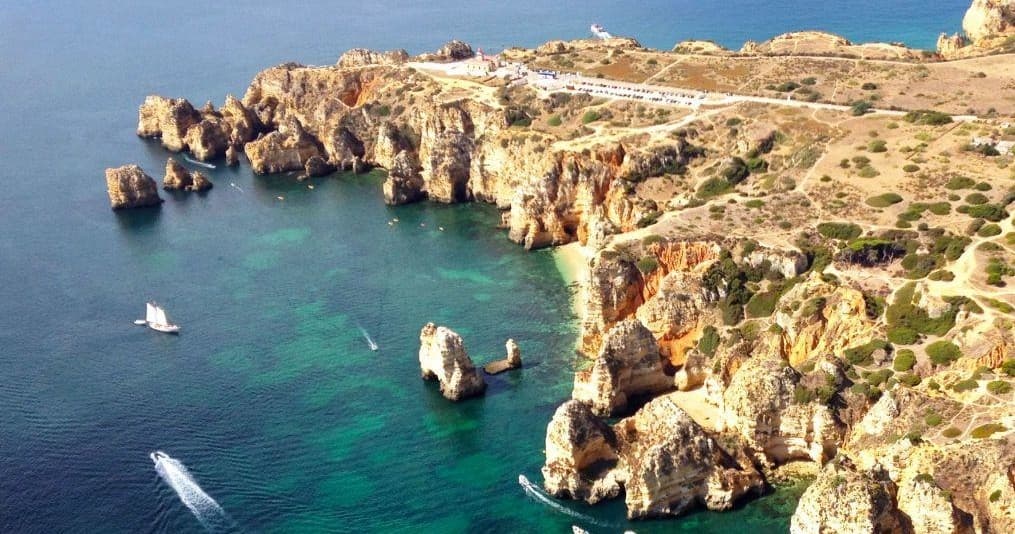 Aerial view of Algarve cliffs and turquoise bays with boats