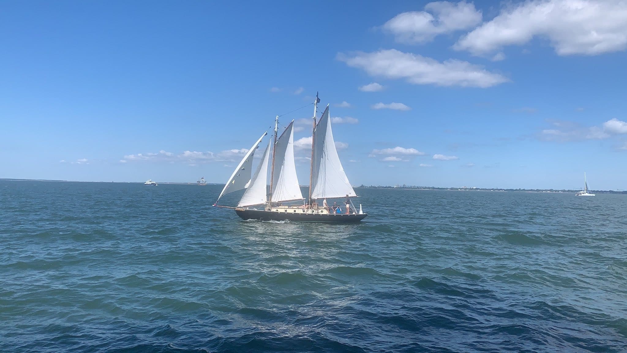 Two-masted schooner sailing on calm blue ocean under clear sky