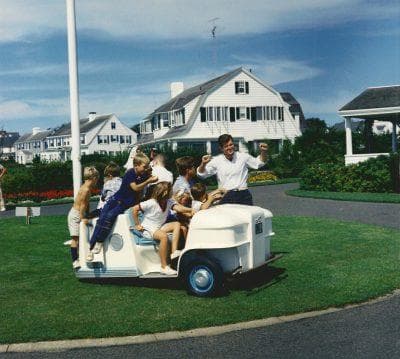 Family riding a golf cart on Hyannis Port lawn by the house