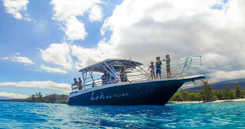 Charter boat anchored in bright tropical sea under dramatic clouds