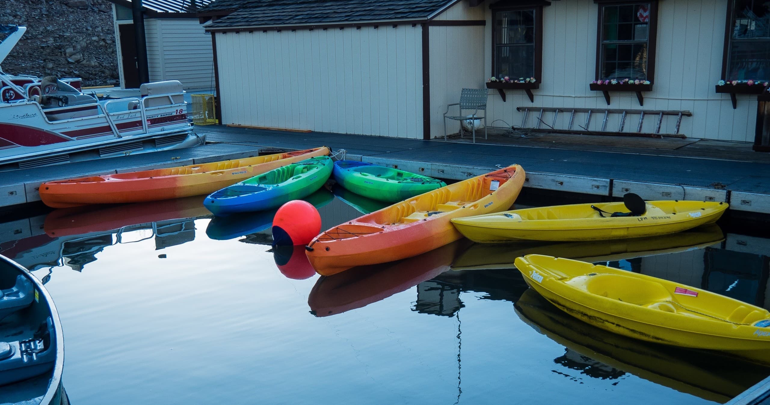 Bright kayaks moored at dock reflecting in still water