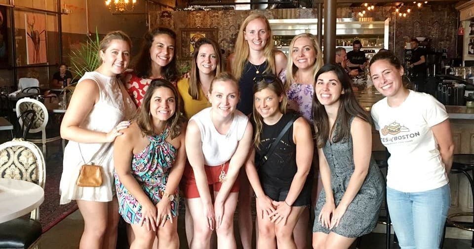 Group of women smiling at urban cafe during Boston food tour