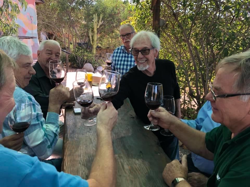 Group enjoying outdoor wine tasting at rustic vineyard picnic table