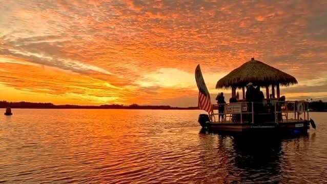 Tiki boat cruising at sunset on calm river in Florida