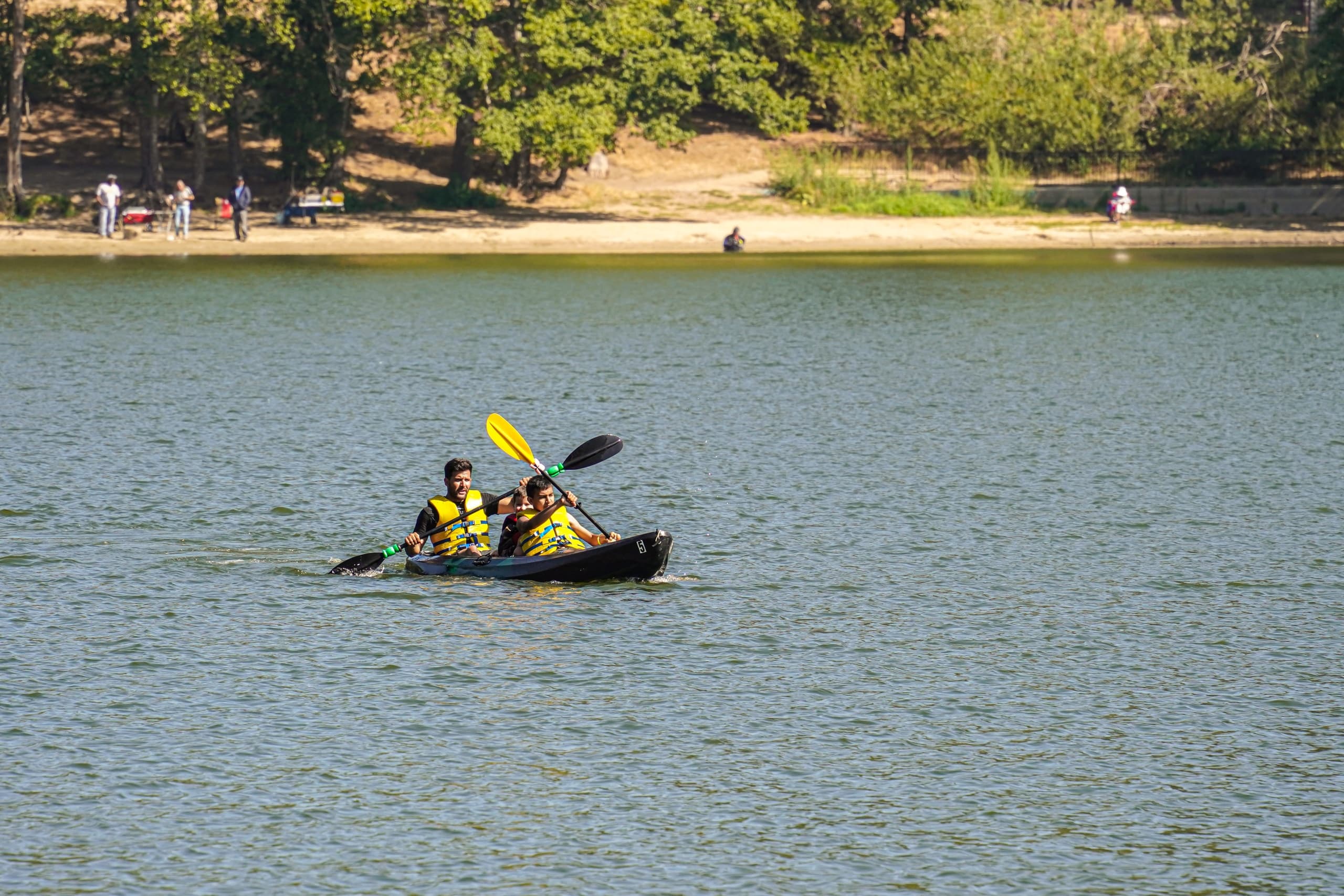 Two kayakers paddling together on open lake near shoreline