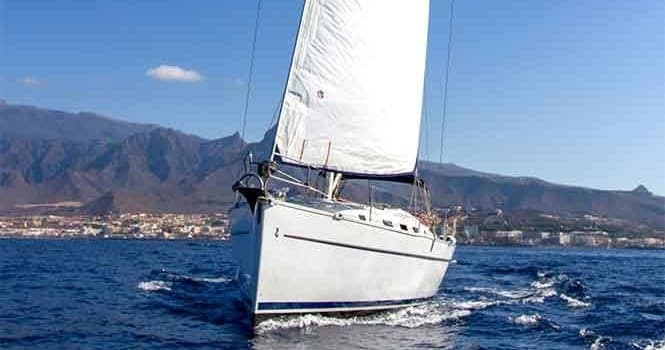 Charter sailboat near Tenerife shore with mountainous backdrop
