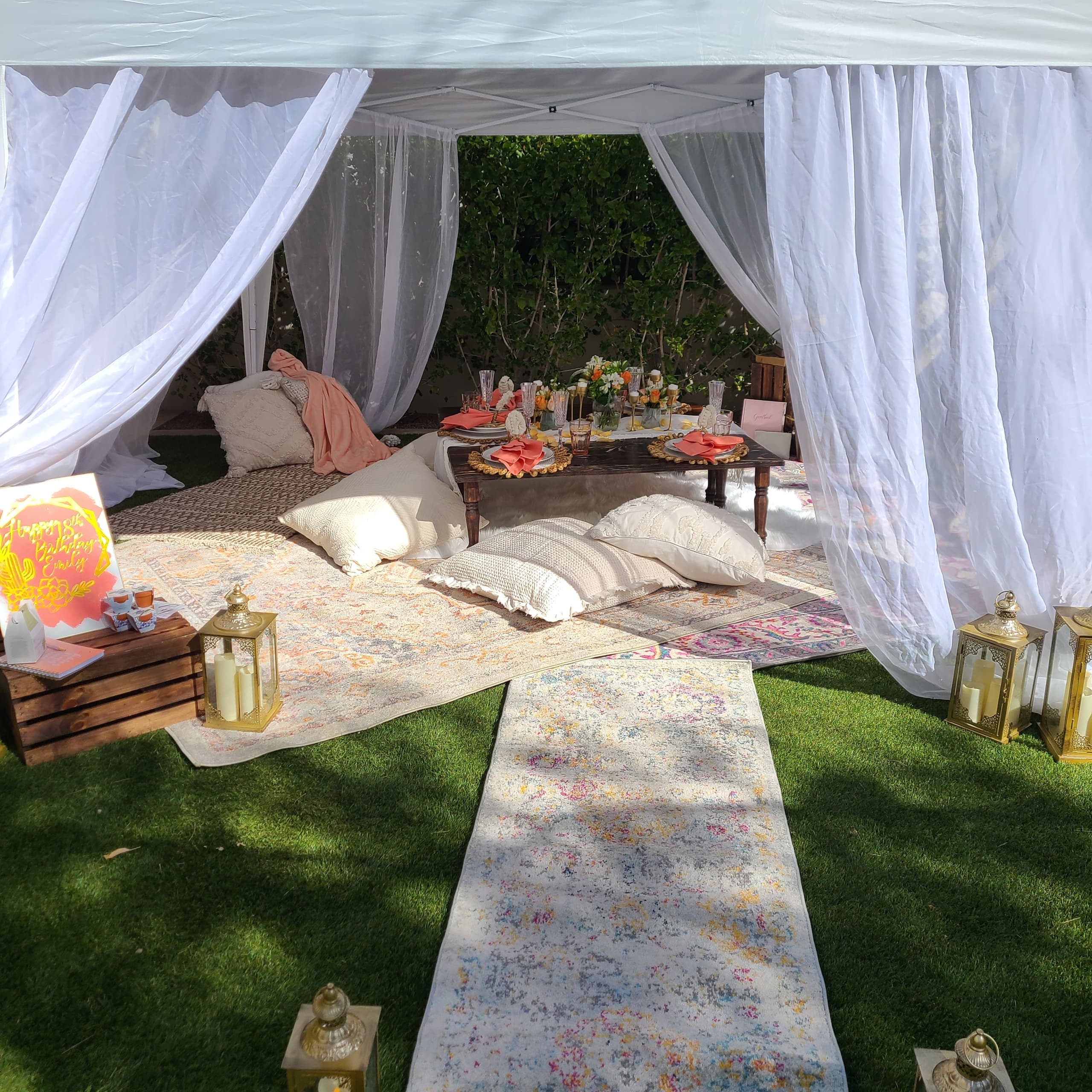 Boho picnic lounge under canopy tent on backyard lawn