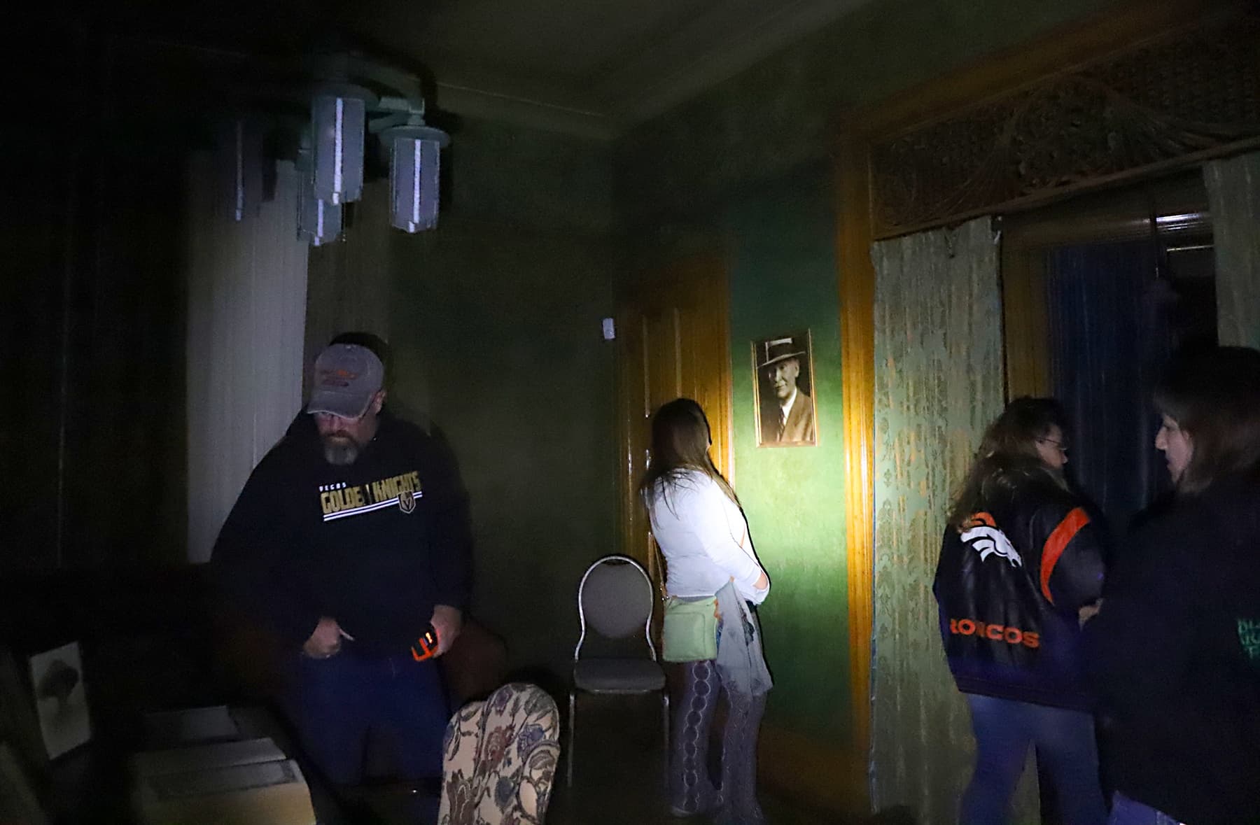 Ghost tour group exploring historic Deadwood parlor by flashlight