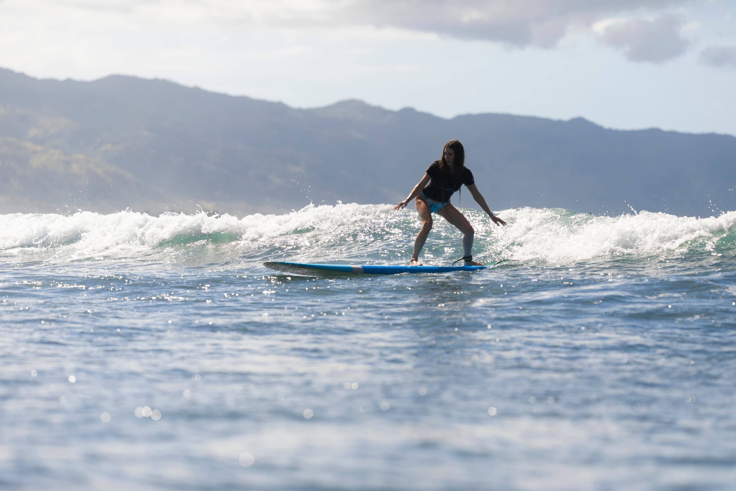 Stand-up paddler riding gentle North Shore waves with mountain backdrop