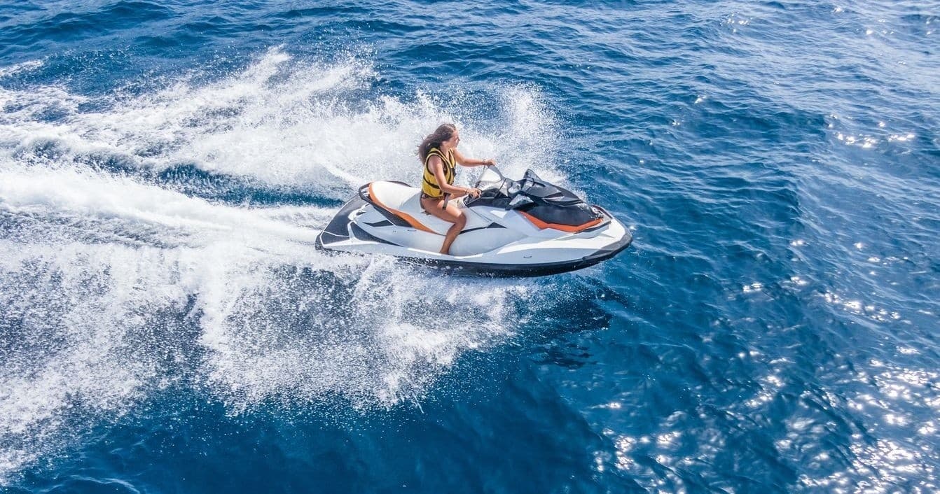 Solo rider on jet ski speeding across open ocean on sunny day