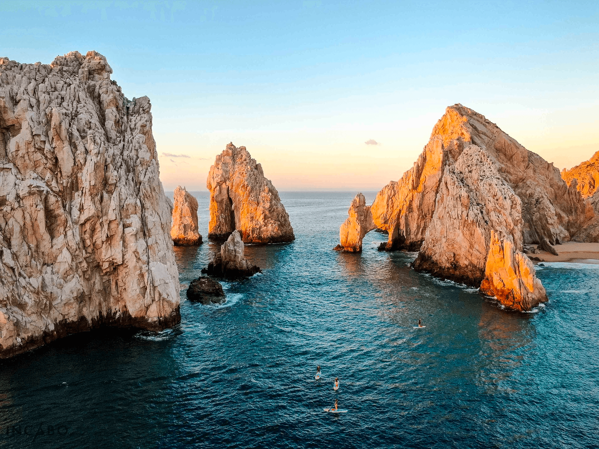 Sunset at Cabo rock arches with boat cruising near shore