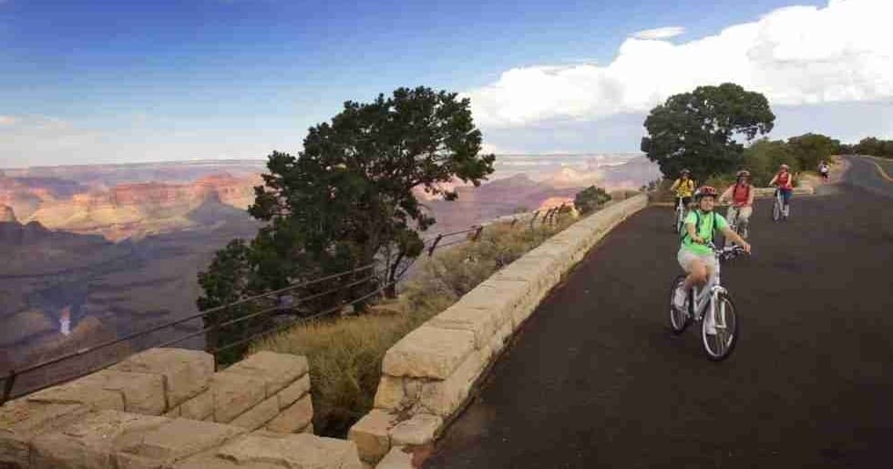 Cyclists riding along scenic Grand Canyon rim road at sunset
