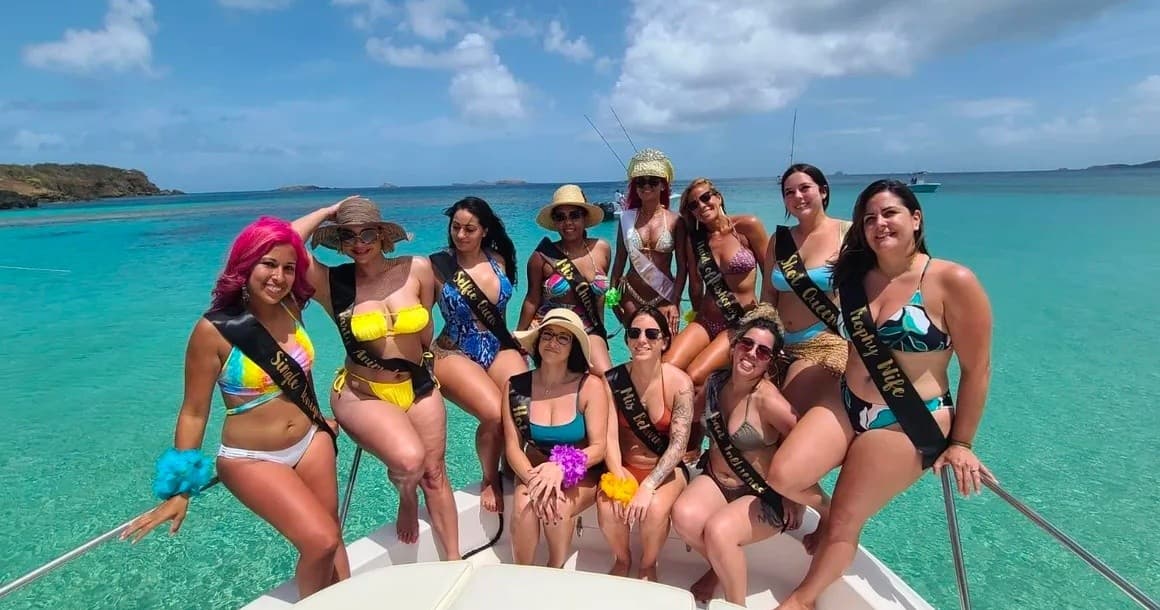 Group bachelorette on boat in shallow turquoise lagoon, partying