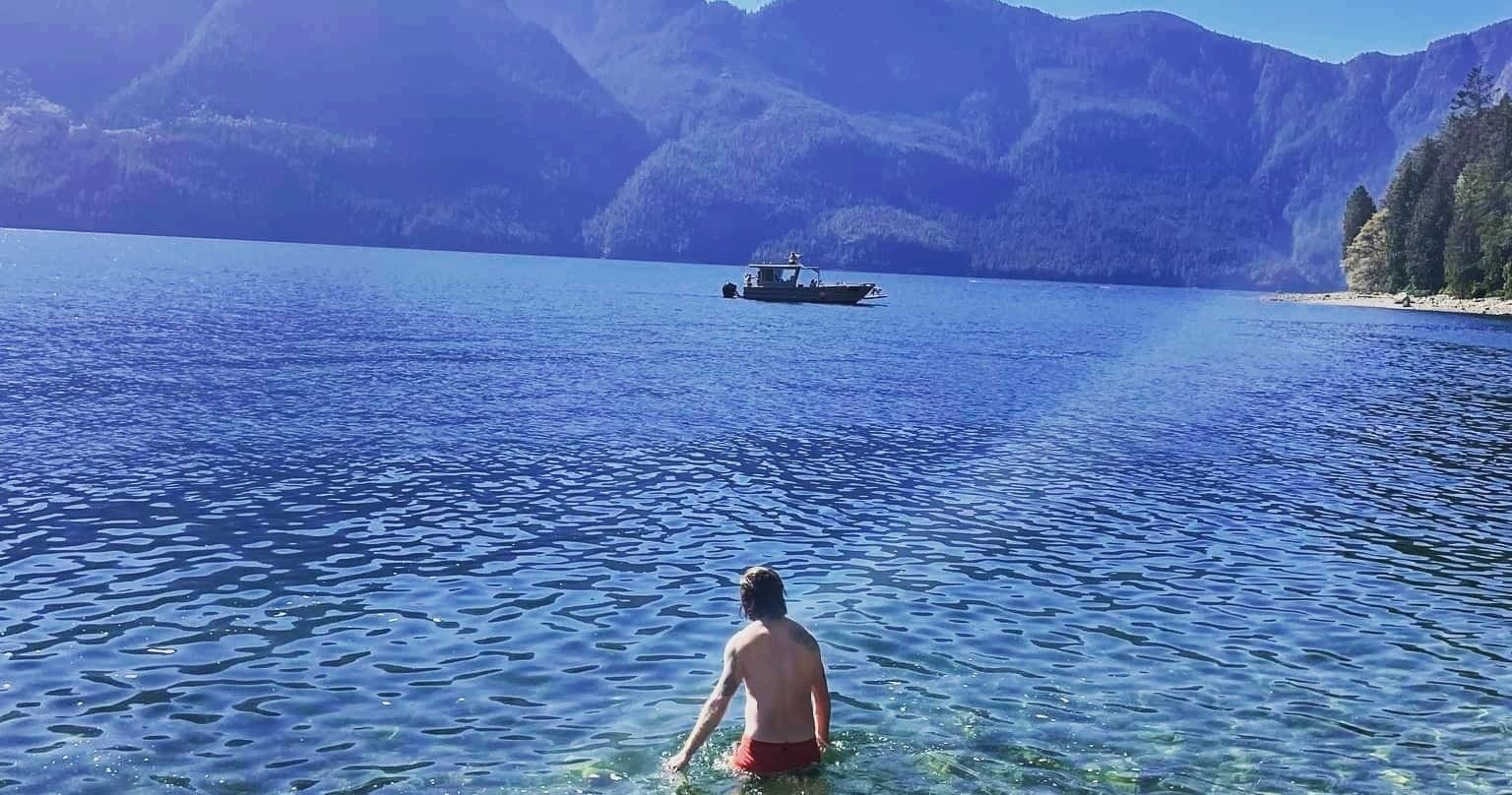 Swimmer wading into crystal lake with mountain backdrop