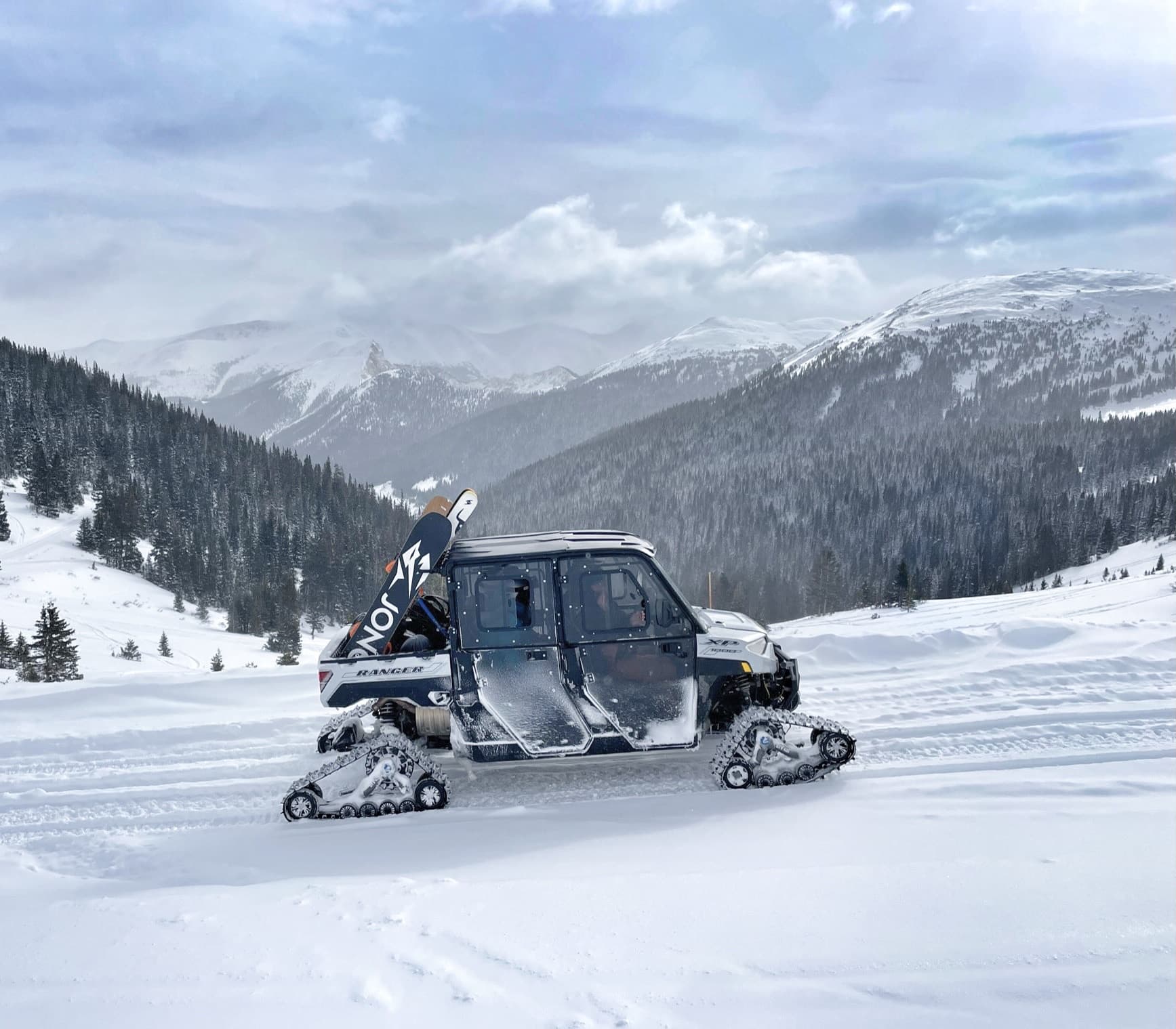 Snowcat carrying skiers across snowy alpine backcountry terrain