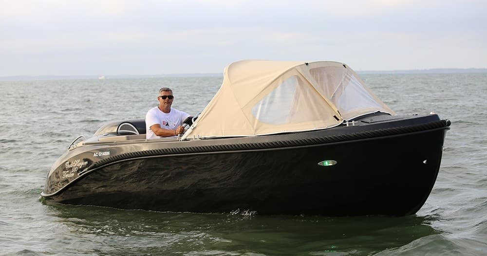 Black motorboat cruising open coastal waters with captain