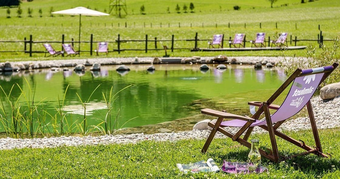 Relaxing lakeside pond with lounge chairs and green meadow