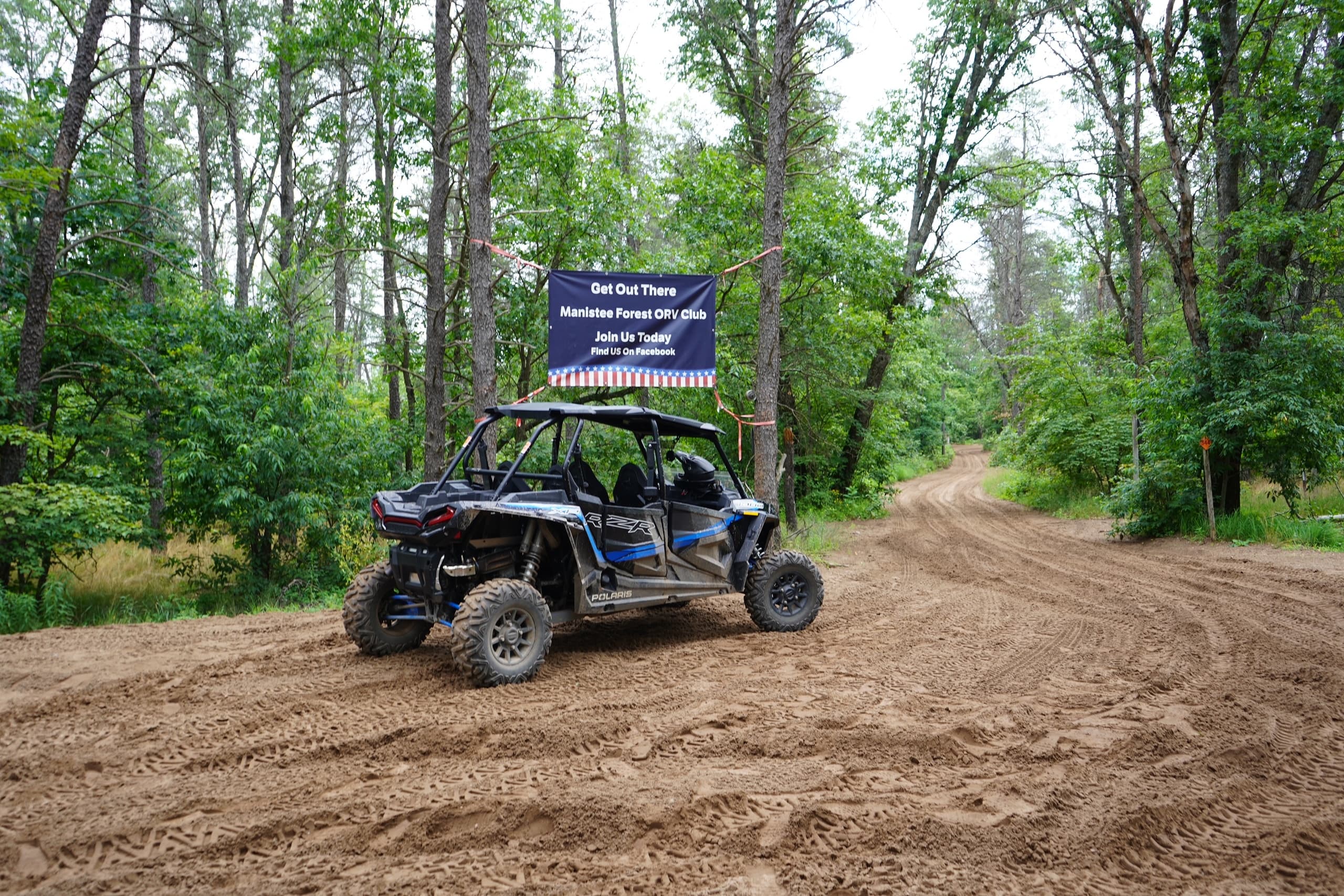 UTV side-by-side on sandy trail at forested campground