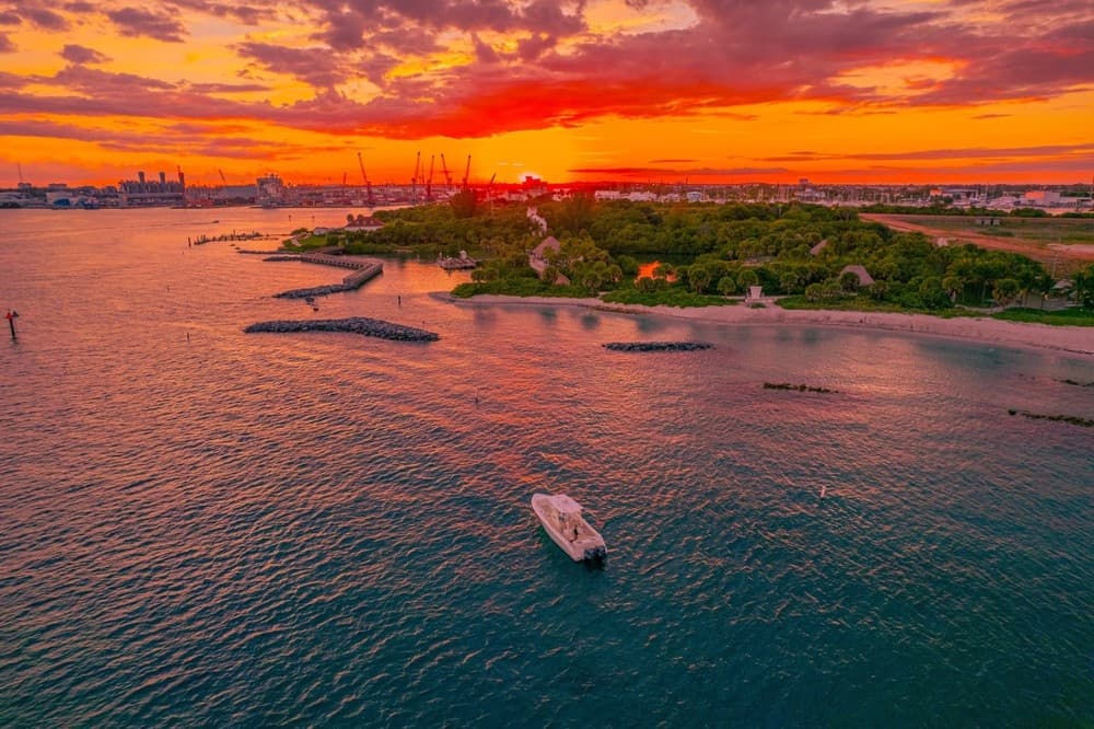 Aerial sunset over coastal waters and boat near shoreline