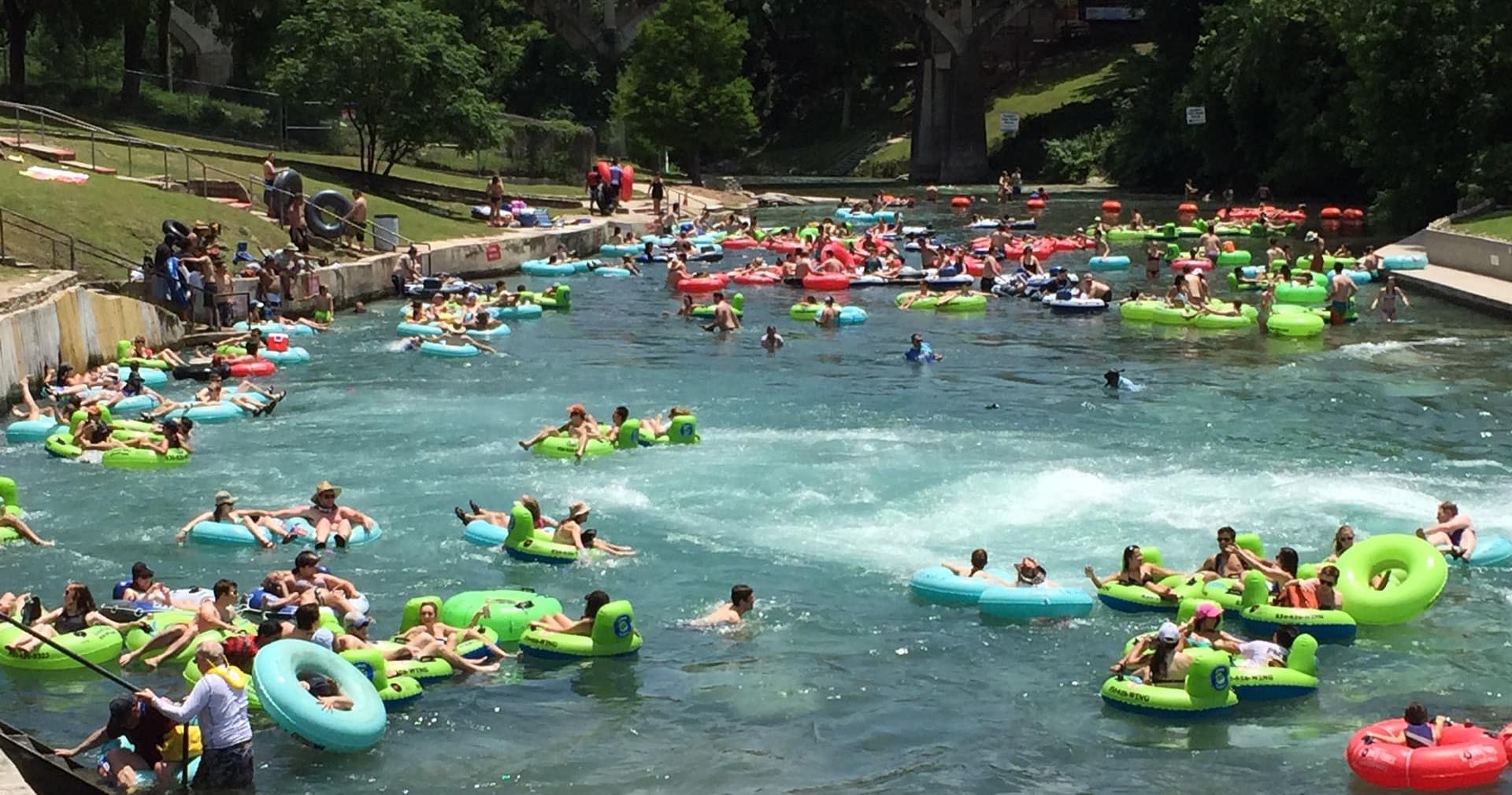 Crowded river tubing with colorful inner tubes on calm water