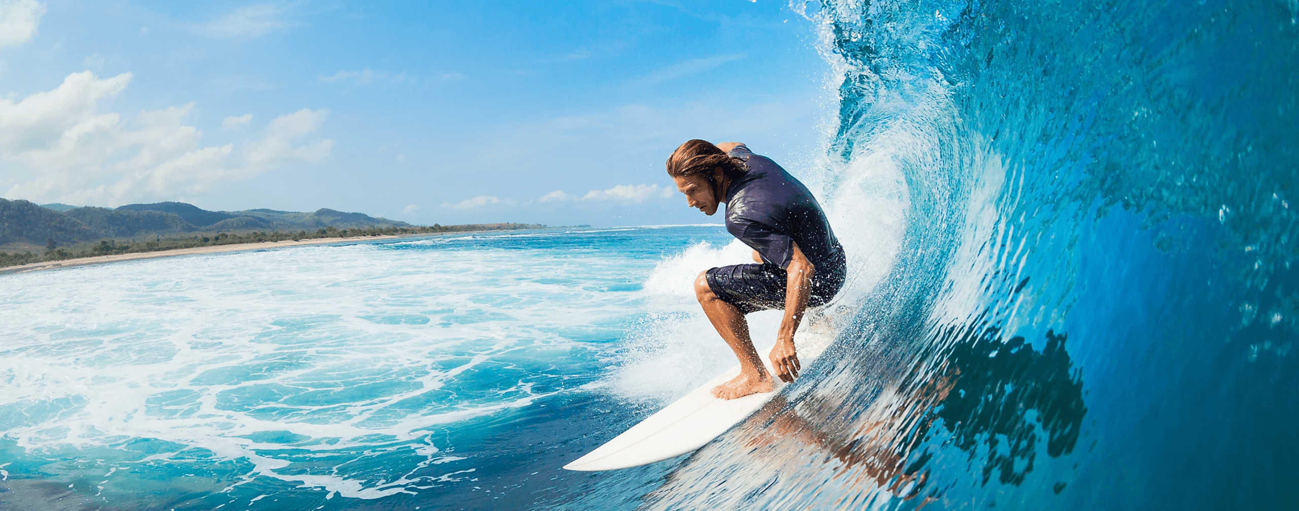 Surfer riding a blue barreling wave on tropical Kauai coast