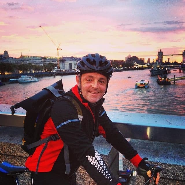 Smiling cyclist at riverside sunset on urban waterfront ride