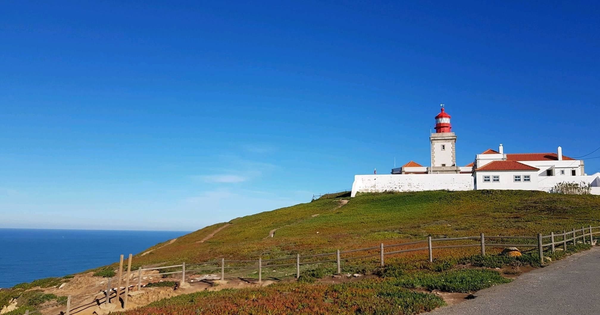 Lighthouse on rocky Atlantic cliffs, panoramic coastal hike view