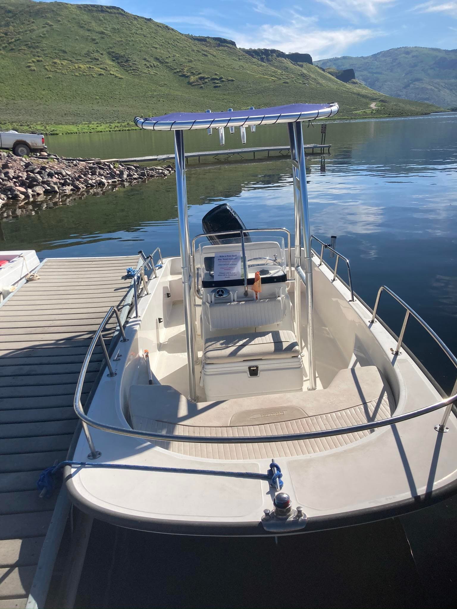 Center-console boat tied at dock on alpine reservoir, day outing