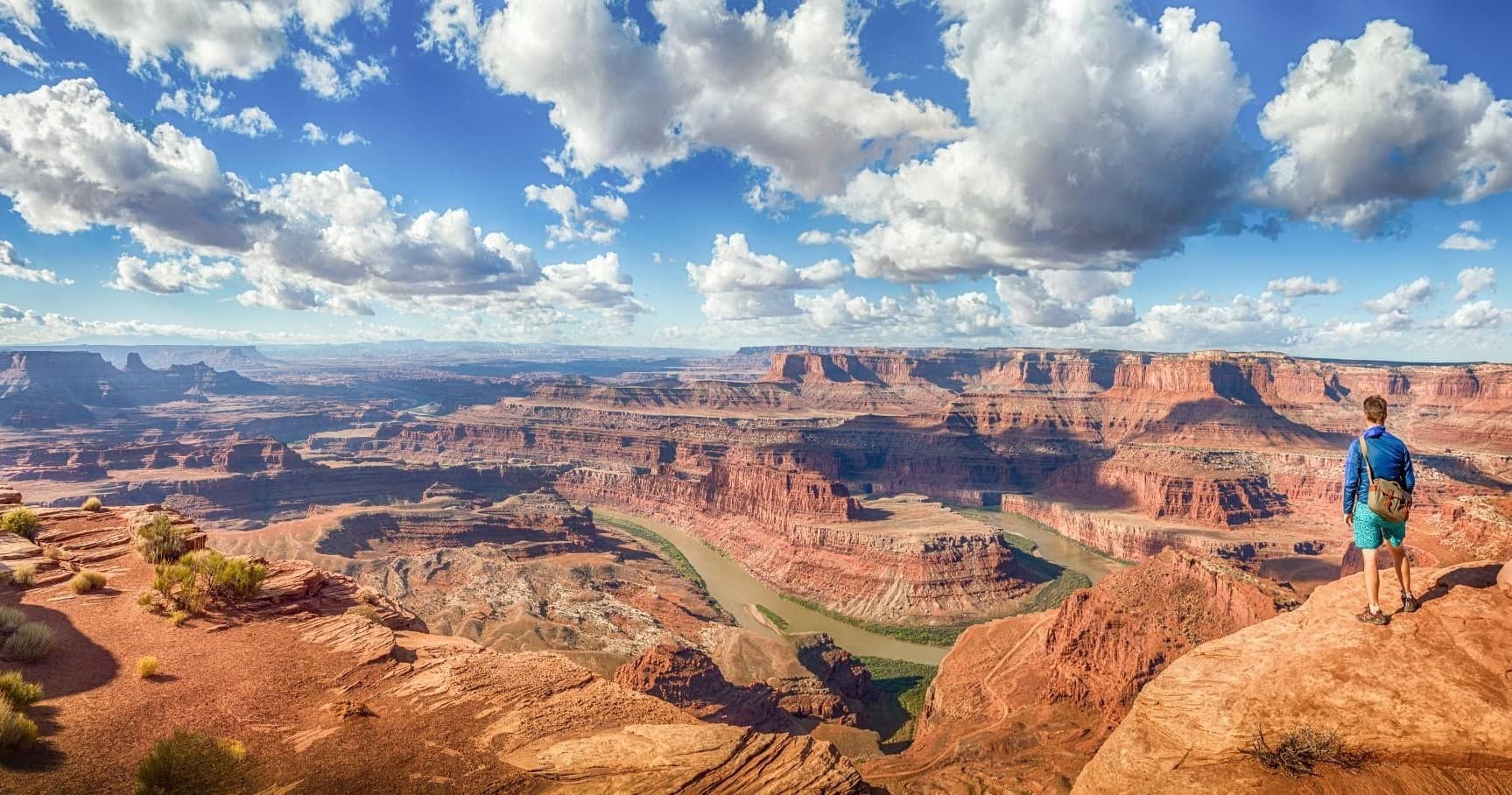 Hiker overlooking sweeping desert canyon panorama at rim