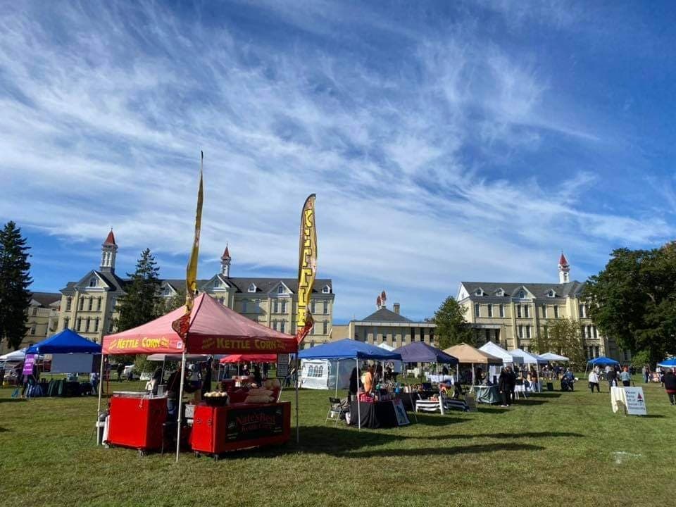 Outdoor festival tents and vendor booths on grassy campus green