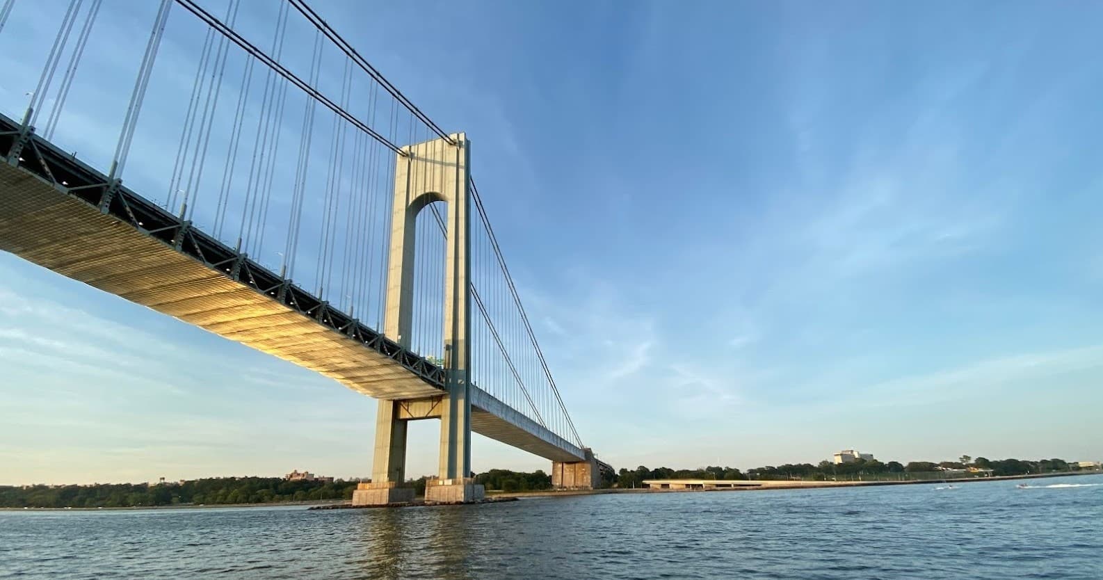 Suspension bridge spanning coastal waters at sunset from boat