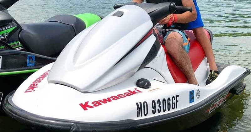 Close-up of Kawasaki jet ski docked, riders prepping on calm water