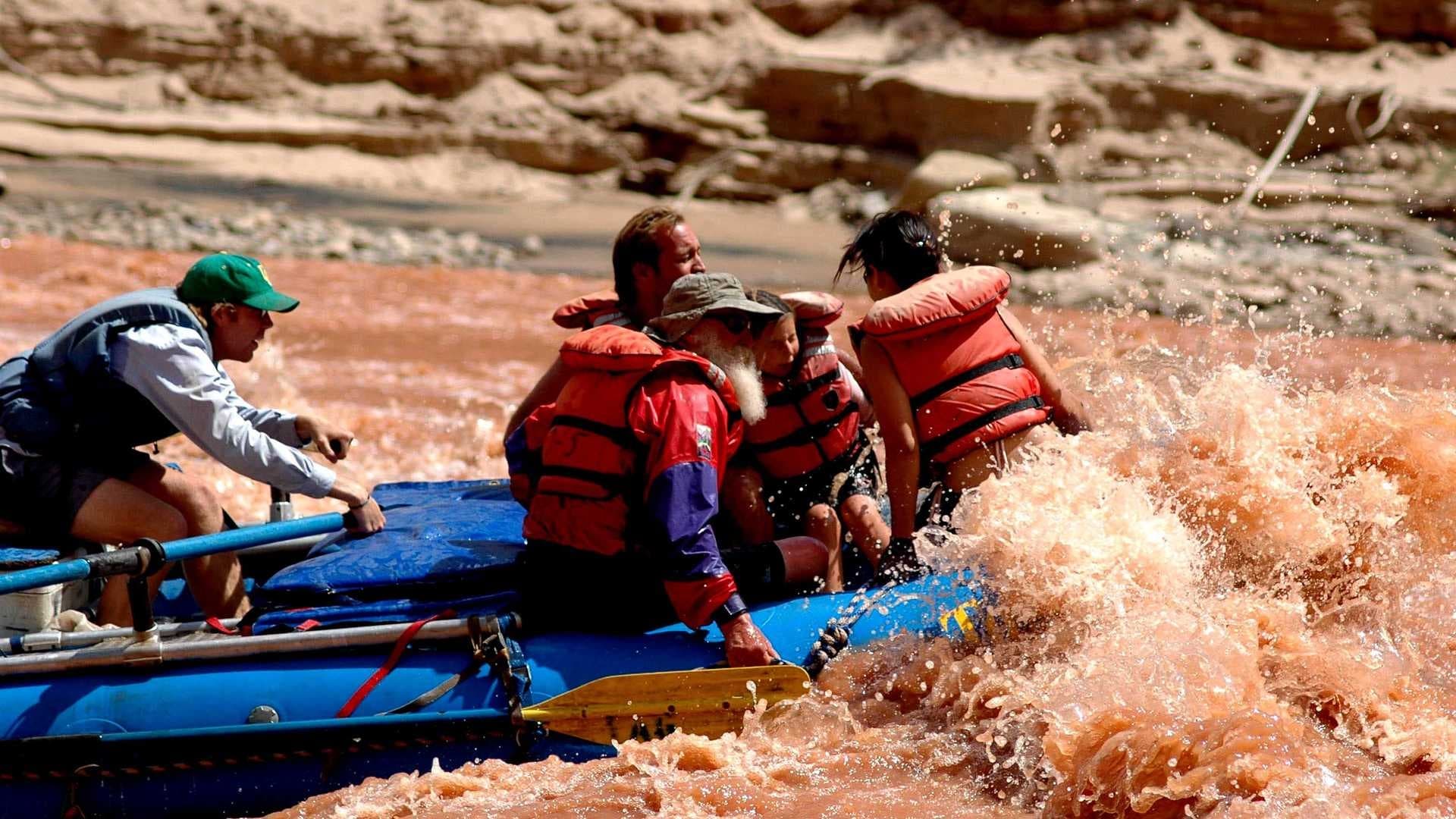 Whitewater rafters navigating muddy rapids on guided river trip