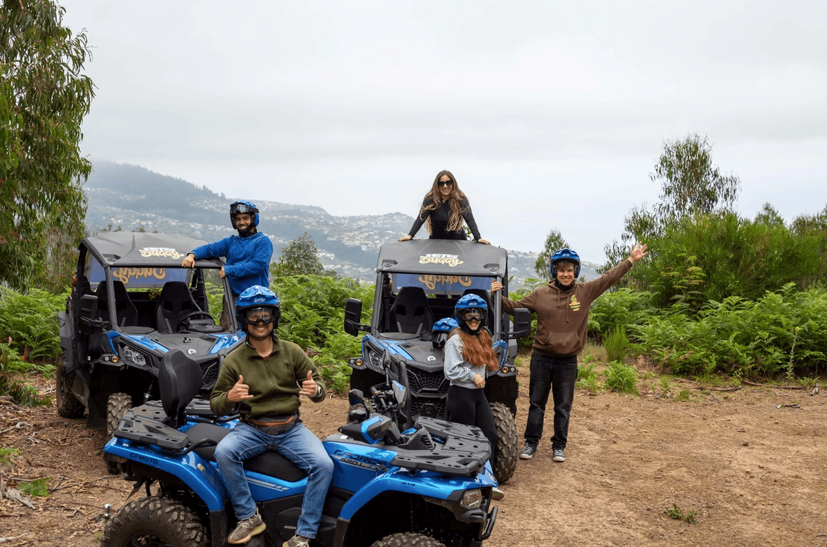 Group of buggies and ATVs with riders on a coastal hillside trail
