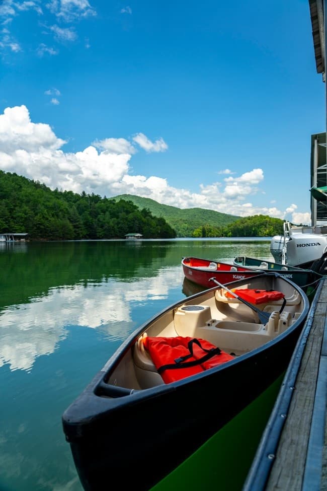 Canoes docked on tranquil mountain lake with blue skies