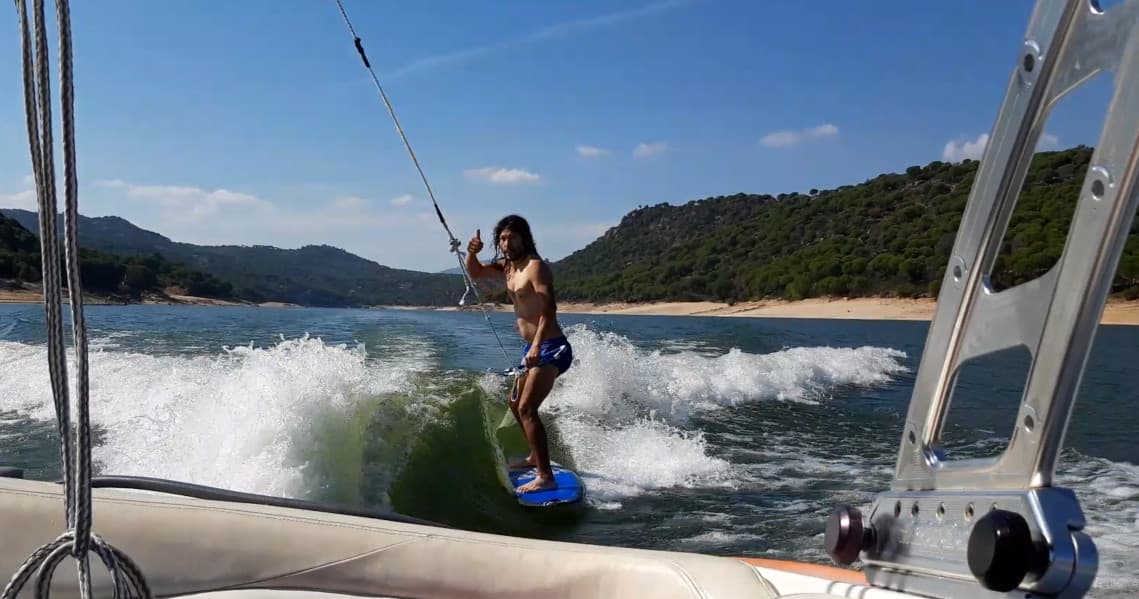 Wakesurfer riding boat wake with mountainous shoreline background