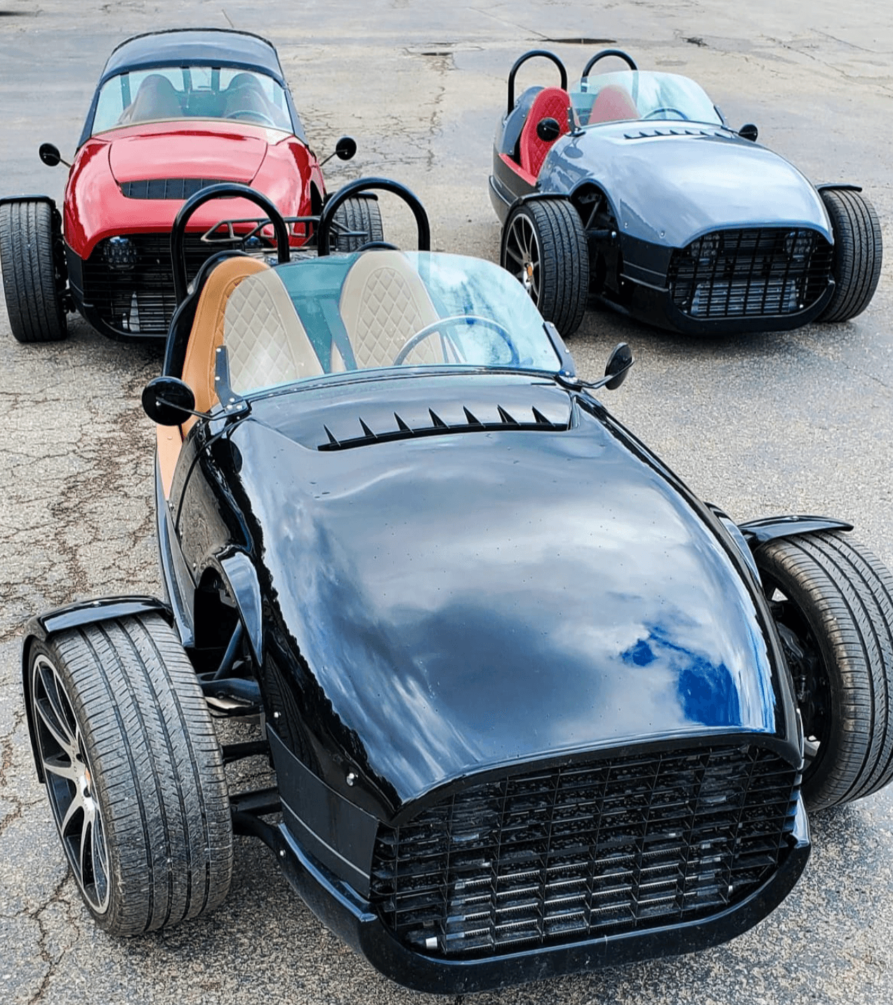 Three open-top sports cars on paved lot for scenic drive