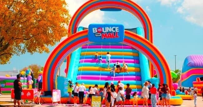 Families on colorful outdoor inflatable slide at park event