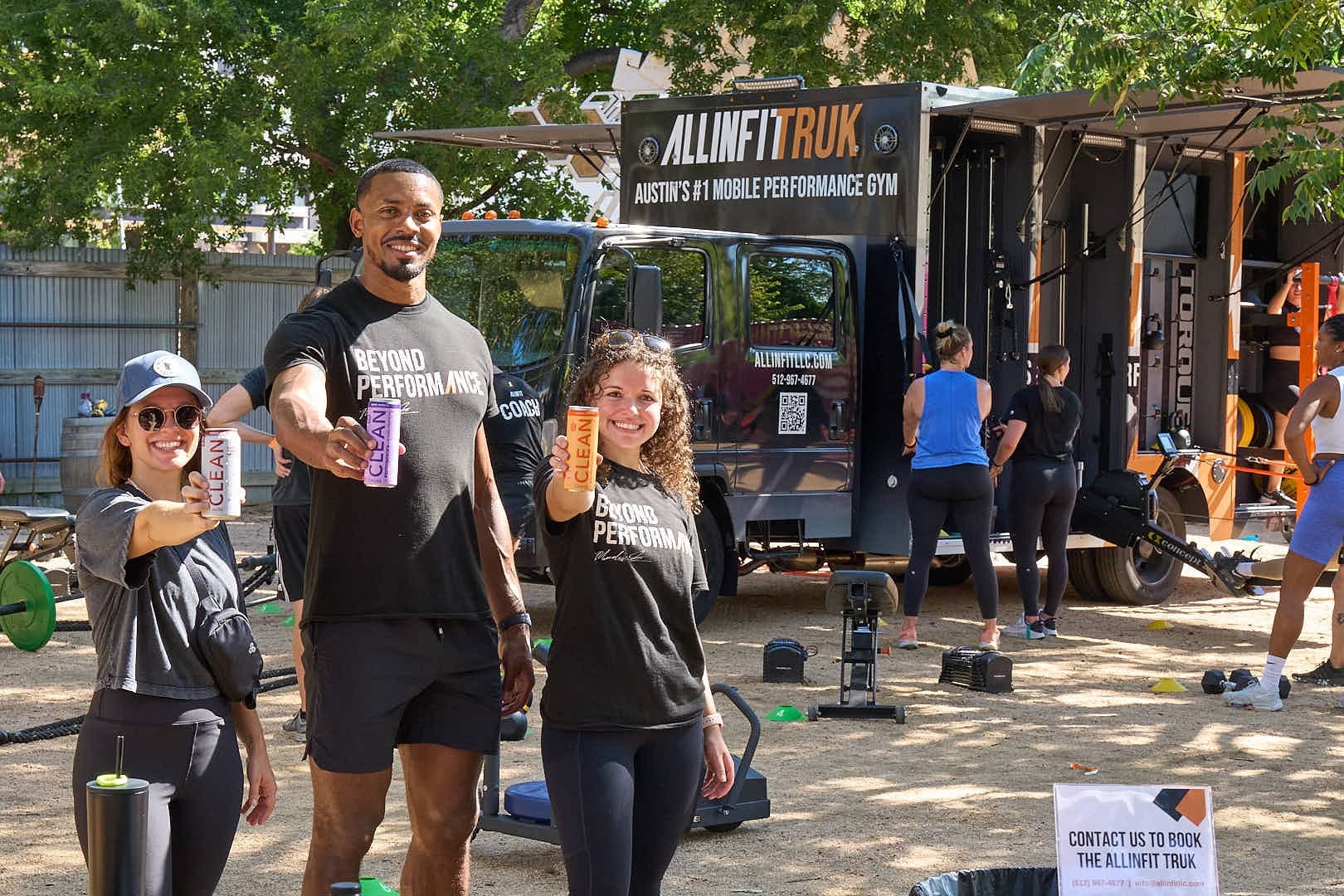 Instructors and members smiling with gear near fitness truck