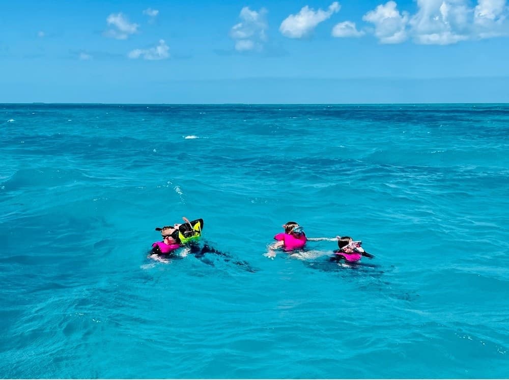Three snorkelers floating over vivid coral reef in Key West waters