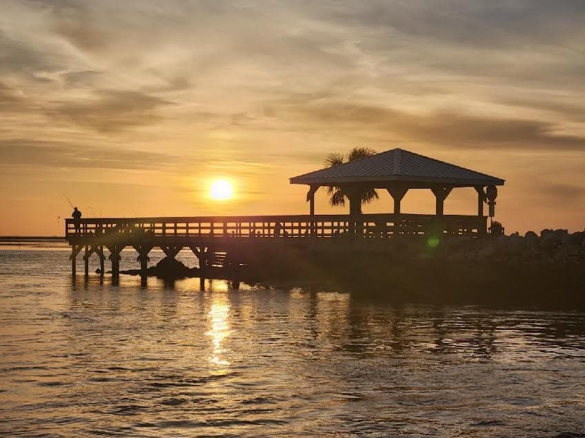 Wooden pier pavilion at sunset over reflective coastal waters