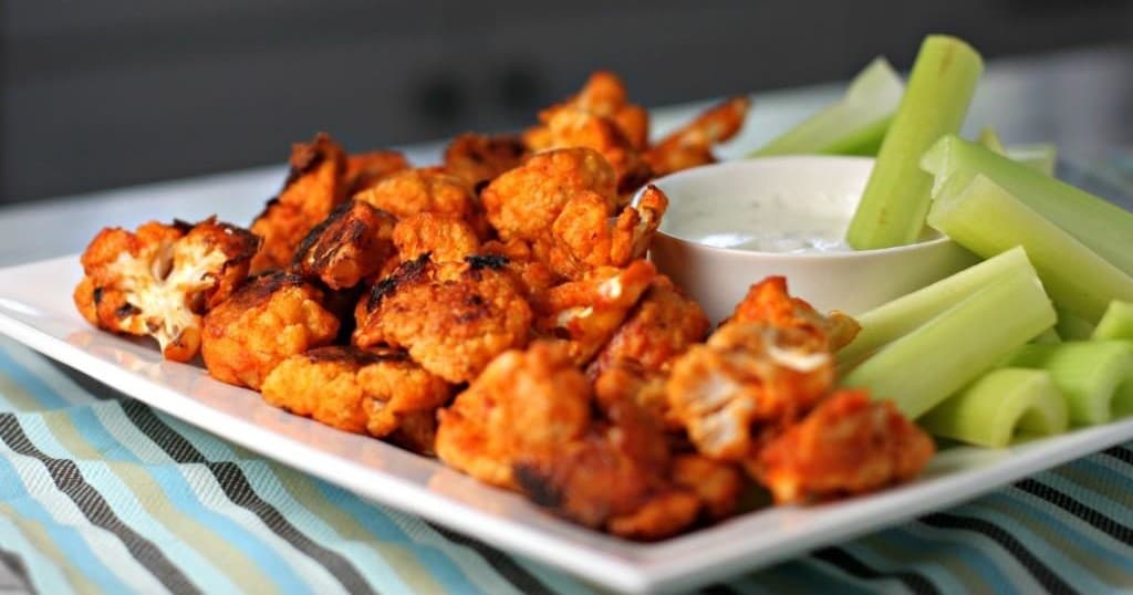 Buffalo-style cauliflower bites with celery and dip on plate
