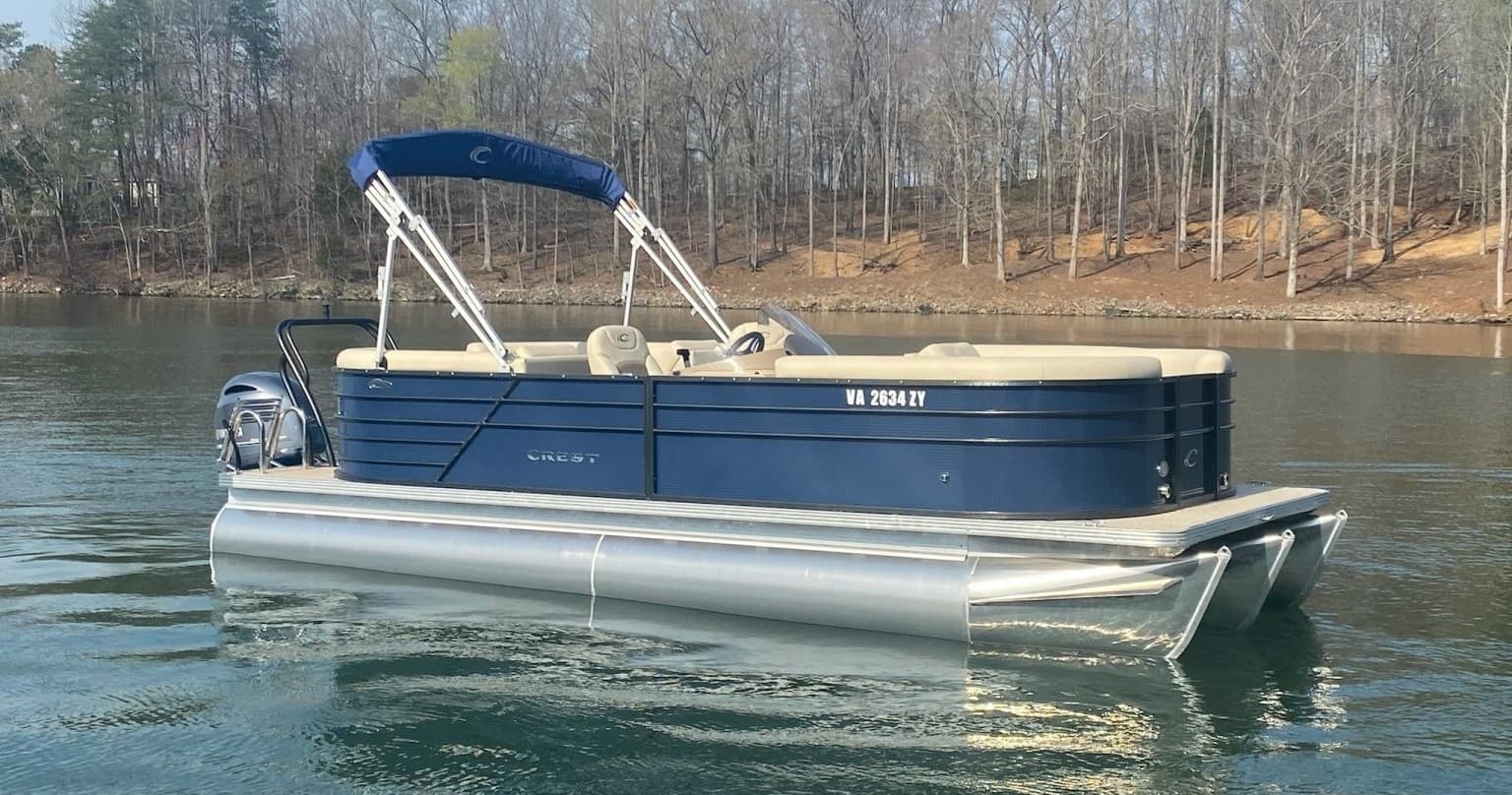 Blue pontoon boat floating on serene lake near wooded shore