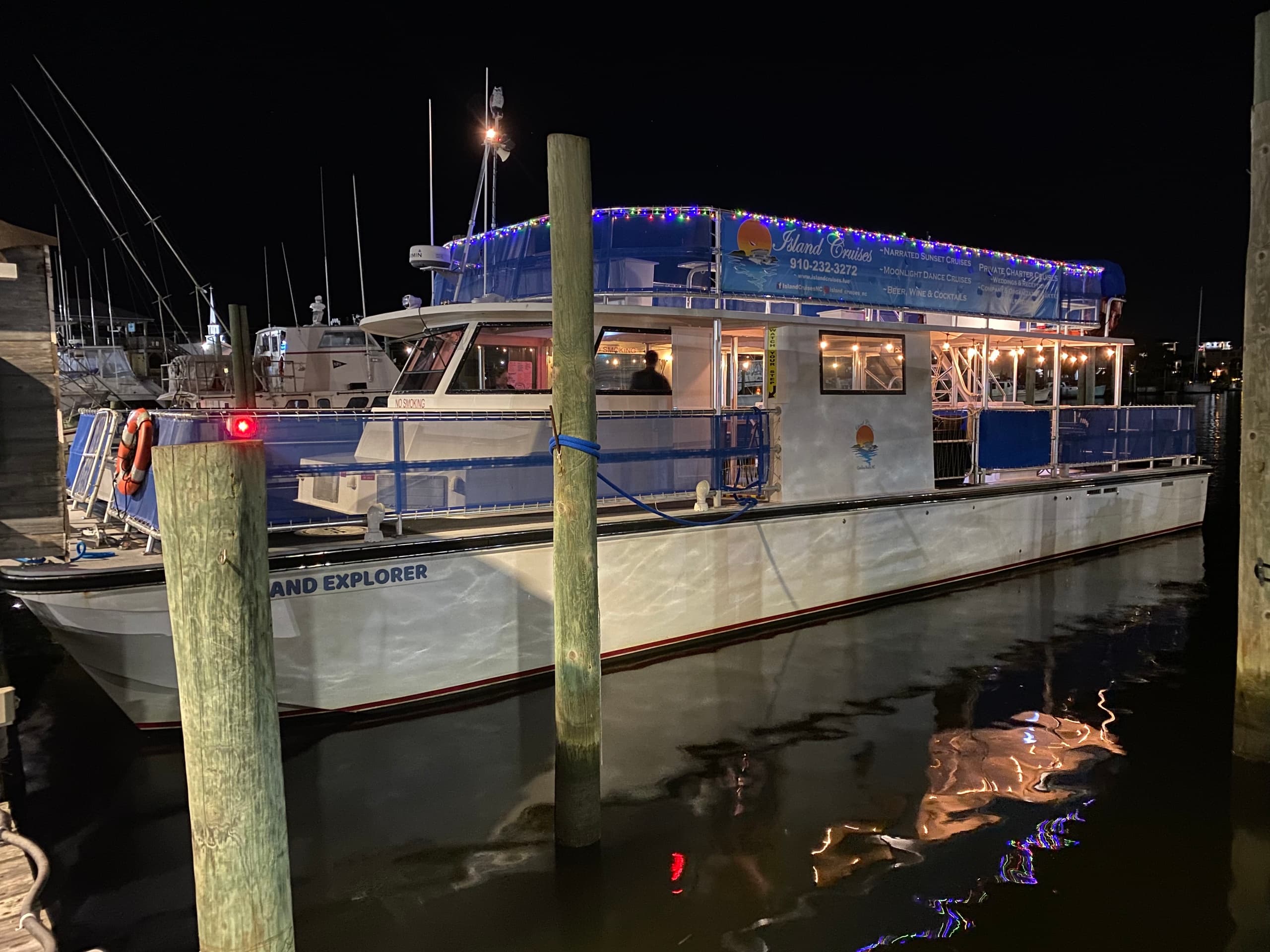 Nighttime island cruise boat docked, lit deck and reflection