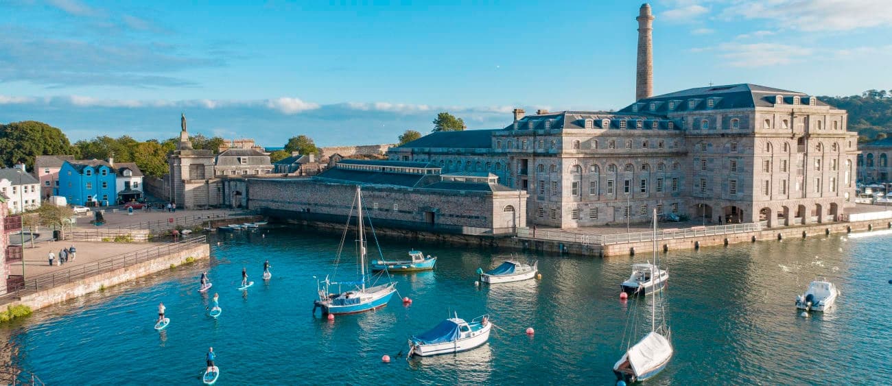 Sailboats moored in historic harbor with waterfront buildings